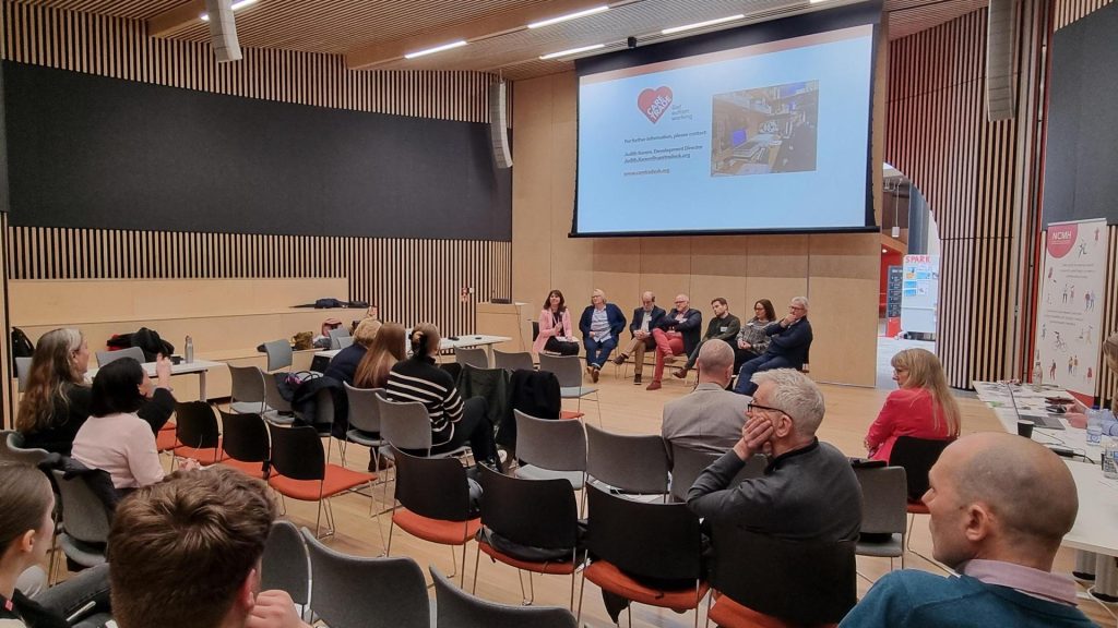 Wide angle shot of the speaker's panel and the audience asking questions in the lecture theatre