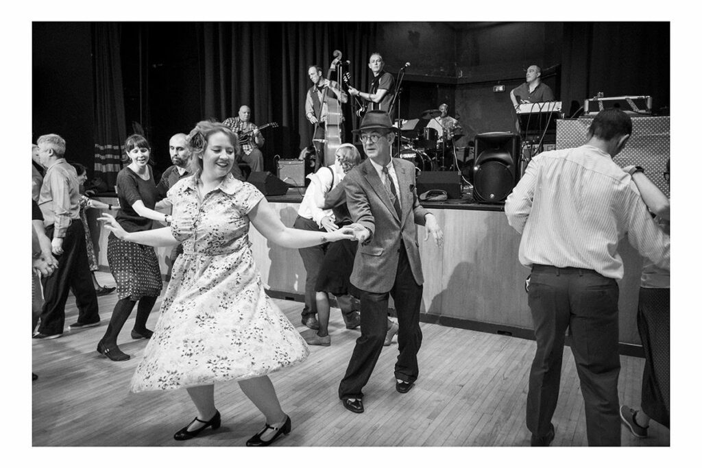 Black and white photo of Catrin dancing with male partner in front of live band