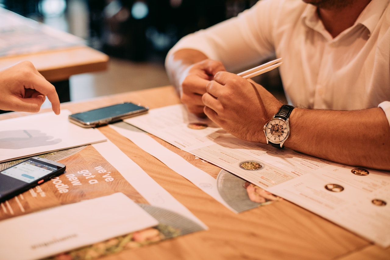 a close photo of from the neck down of two people sat at a restaurant table